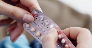 Die Hände einer Frau drücken eine Antibabypille aus dem Pillenblister