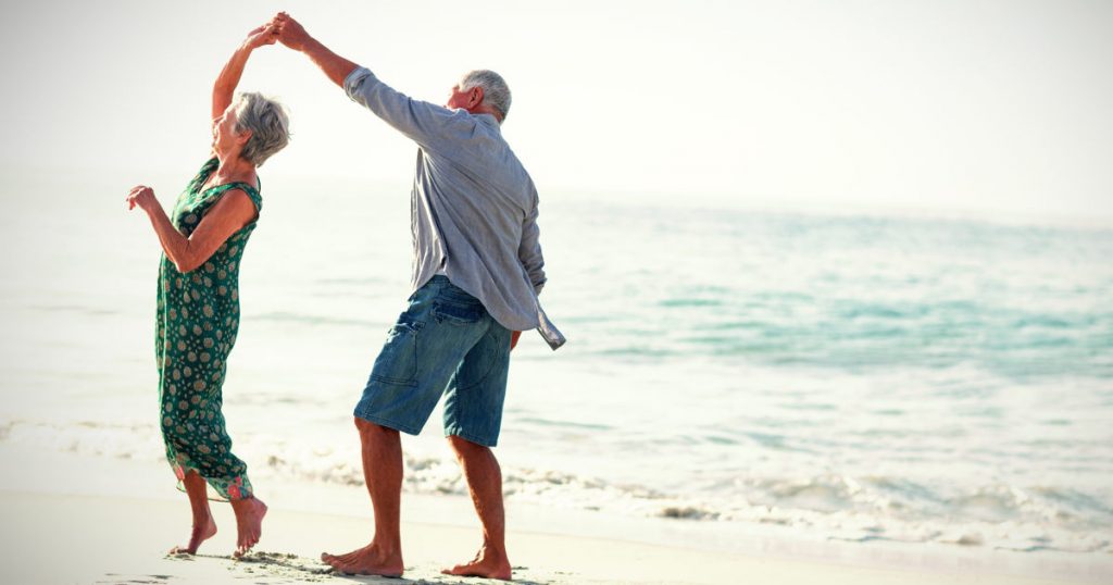 ein älteres Ehepaar tanzt am Strand und ist glücklich in Bewegung