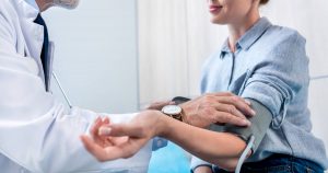 Ein Arzt misst bei einer Patientin den Blutdruck mit einem Blutdruckmessgerät