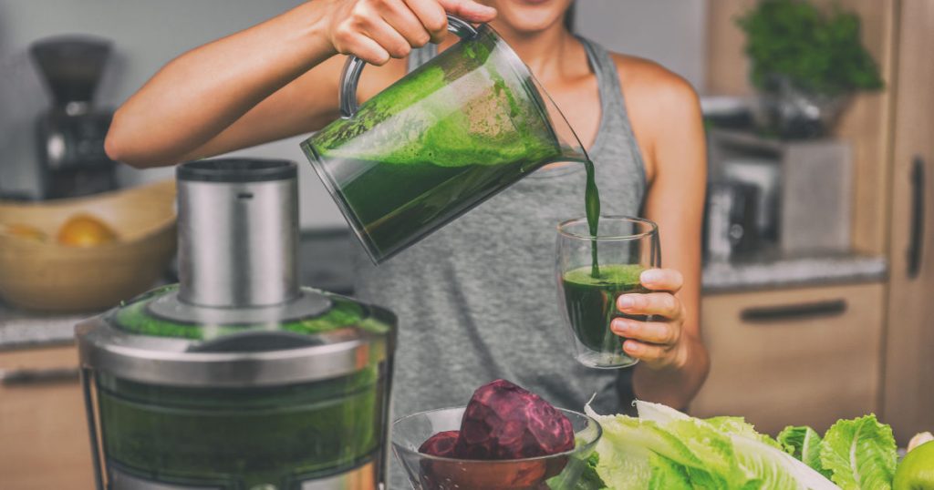 Eine Frau bereitet sich einen grünen Detox-Smoothie aus grünen Blattsalaten und Superfoods zu.