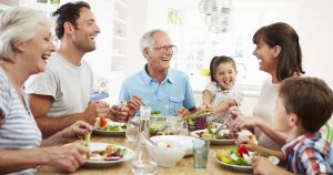 Mehrere Generationen einer Familie sitzen gemeinsam am Tisch und essen zusammen gesundes Essen