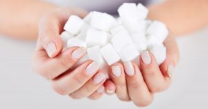 Zu sehen sind Frauenhände, die mit Würfelzucker gefüllt sind